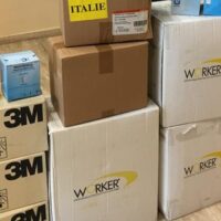 Scatole impilate in magazzino; etichette di marchio 3M e altre confezioni bianche e marroni, contenuti non visibili.