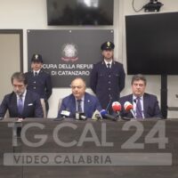 Ufficiali e funzionari in conferenza stampa, seduti dietro un tavolo con microfoni, in un ambiente istituzionale.