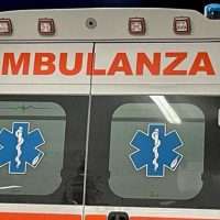 Ambulanza bianca con scritta rossa 'AMBULANZA' e simboli Star di pronto soccorso sulle porte posteriori.